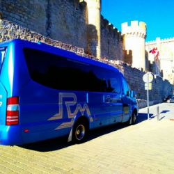 Autobús pequeño azul de Rubimar junto a castillo de Peñafiel